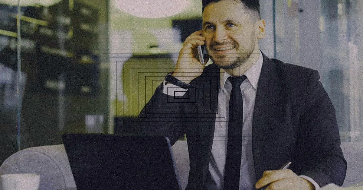 A man using a smartphone while seated at a desk with a microphone, surrounded by cozy decor. — Foto: Benjamin  Dominguez / Pexels